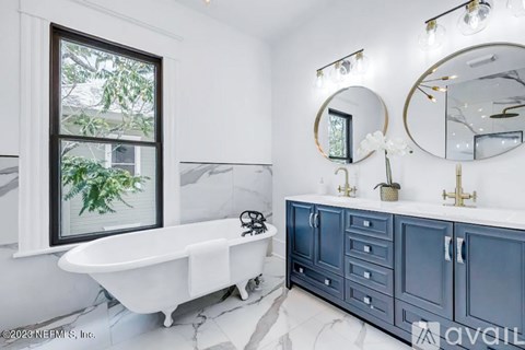 A white bathroom with a blue cabinet and a window.