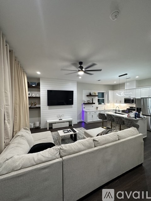 A modern living room with a large couch and a flat screen TV mounted on the wall.