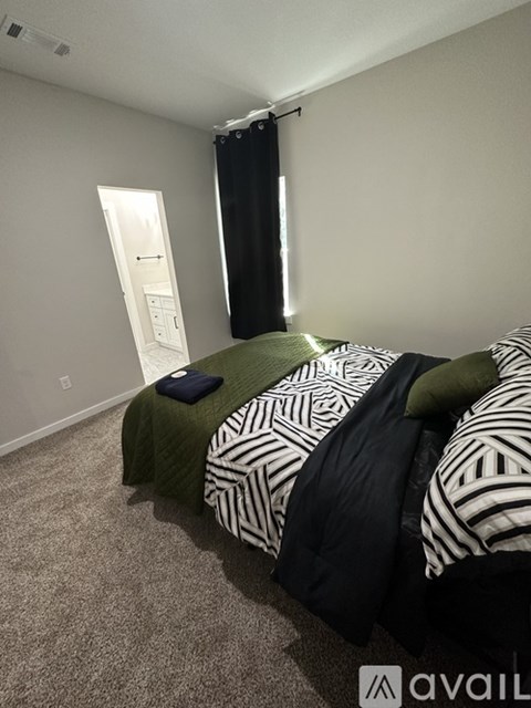 A bedroom with a bed covered in a black and white striped comforter.