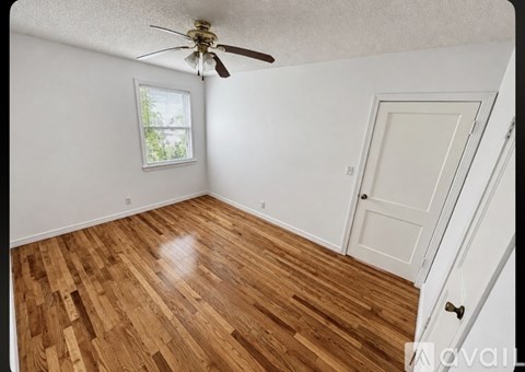 A room with a ceiling fan and wooden flooring.
