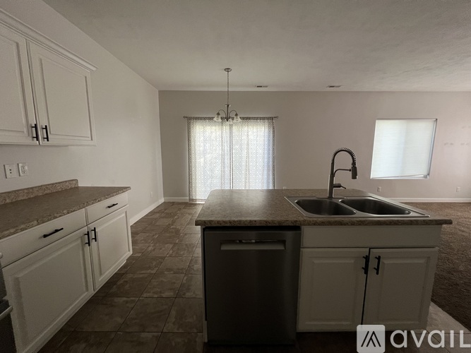 A kitchen with a sink and a window with curtains.