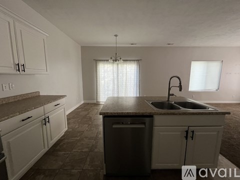A kitchen with a sink and a window with curtains.