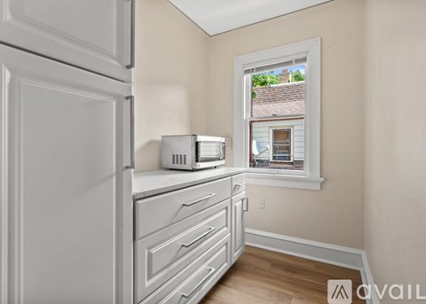 A kitchen with white cabinets and a window.