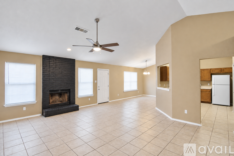 A spacious living room with a fireplace and a ceiling fan.