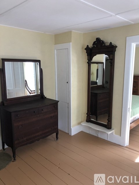 A bedroom with a wooden dresser and a large mirror.
