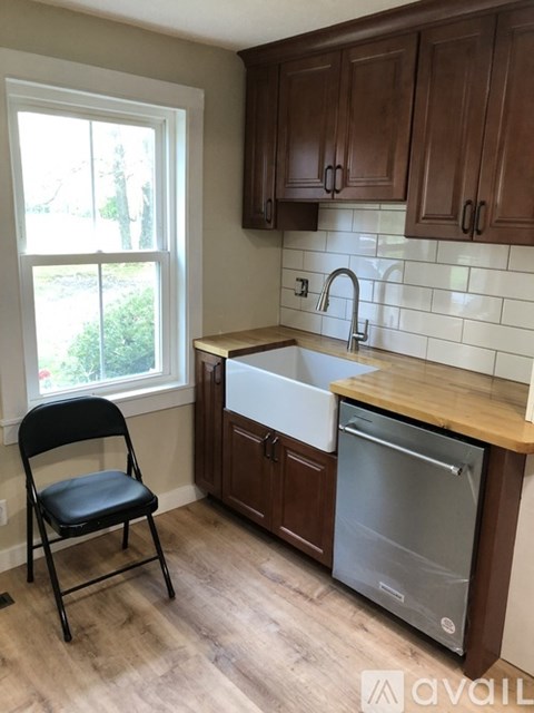 A kitchen with a black chair and a dishwasher.