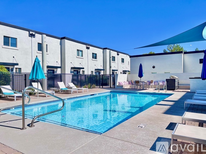 A swimming pool surrounded by lounge chairs and umbrellas in front of a building.