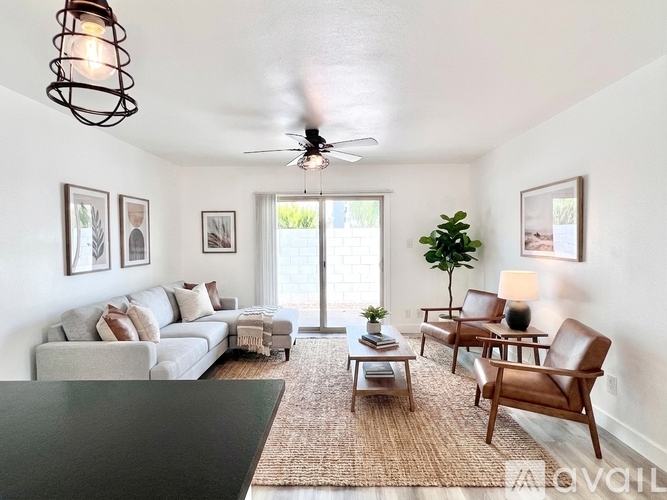 A living room with a grey couch, a coffee table, a ceiling fan, and a rug.