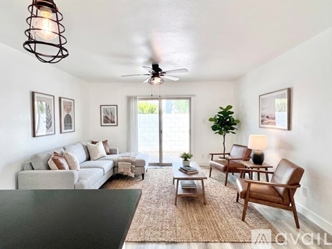 A living room with a grey couch, a coffee table, a ceiling fan, and a rug.