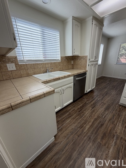 A kitchen with white cabinets and a brown countertop.