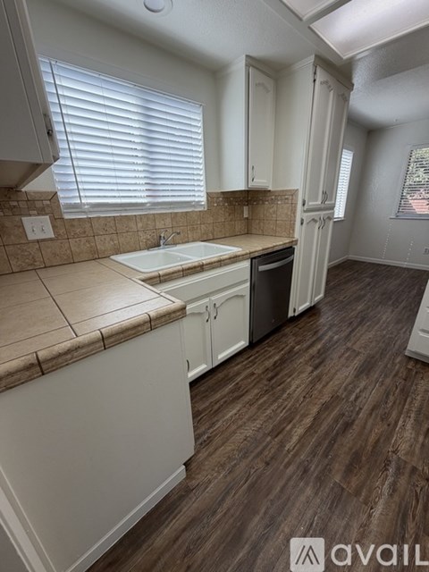 A kitchen with white cabinets and a brown countertop.