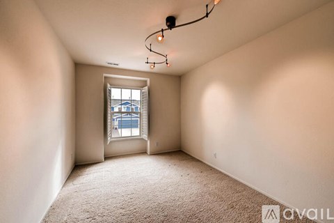 A room with a carpeted floor and a window showing a building outside.