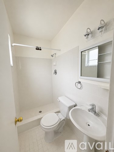 A white bathroom with a toilet, sink and shower.
