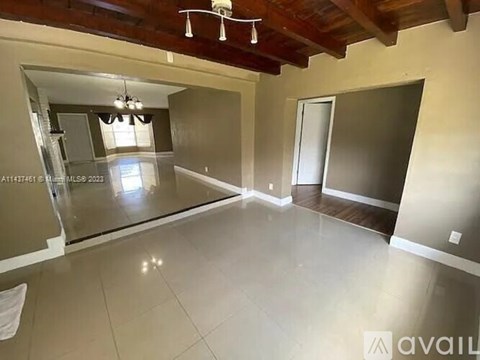 A large, empty room with a wooden ceiling and a glass door leading to another room.