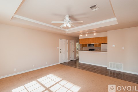 A spacious room with a ceiling fan and a window with sunlight coming through.