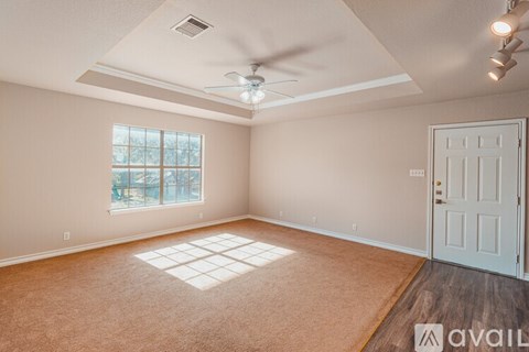 A room with a white door, carpeted floor, and a ceiling fan.