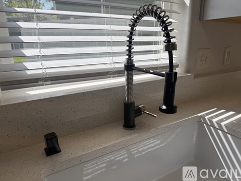 A modern kitchen sink with a black faucet and a black soap dispenser.
