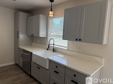 A kitchen with white countertops and grey cabinets.