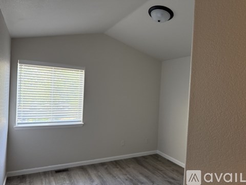 A room with a window and a smoke detector on the ceiling.