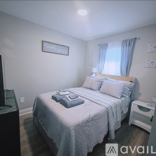 A bedroom with a bed, nightstand, and a framed sign on the wall.