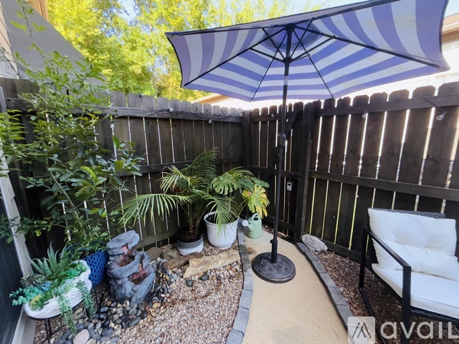 A patio with a striped umbrella and a white chair.