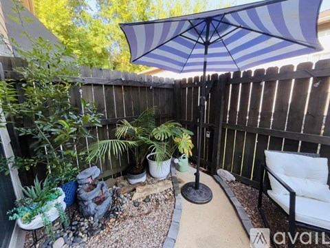A patio with a striped umbrella and a white chair.