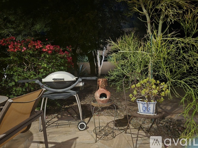 A BBQ grill is on a patio table next to a potted plant.