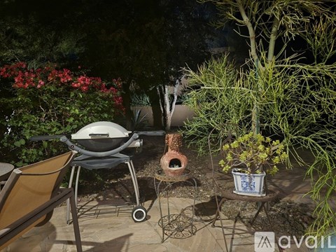 A BBQ grill is on a patio table next to a potted plant.