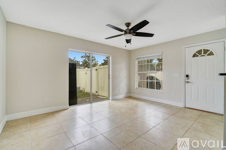 A spacious room with a ceiling fan and sliding glass doors leading to a patio.