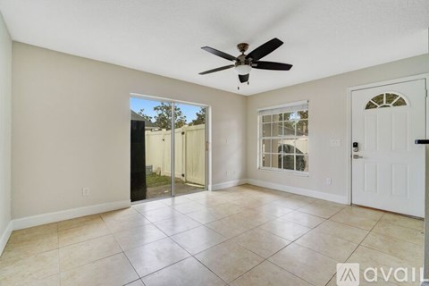 A spacious room with a ceiling fan and sliding glass doors leading to a patio.