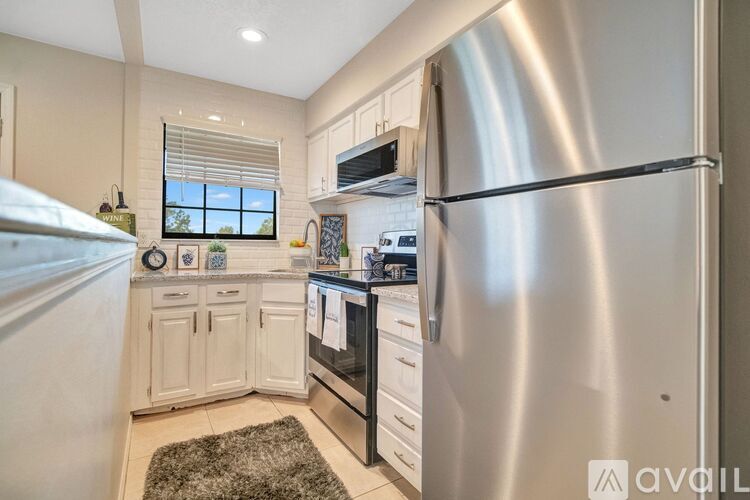 A modern kitchen with a stainless steel refrigerator and white cabinets.