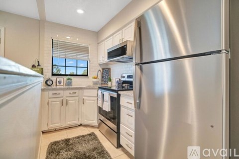 A modern kitchen with a stainless steel refrigerator and white cabinets.