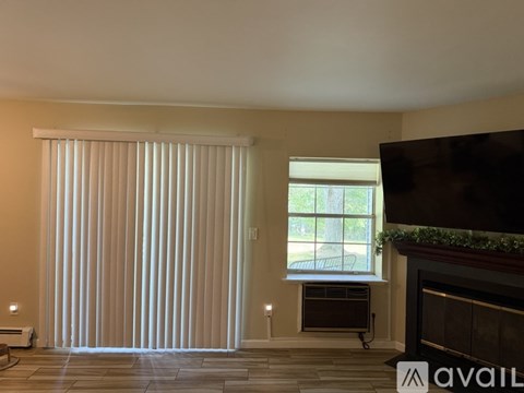 A living room with a fireplace and a large window with blinds.