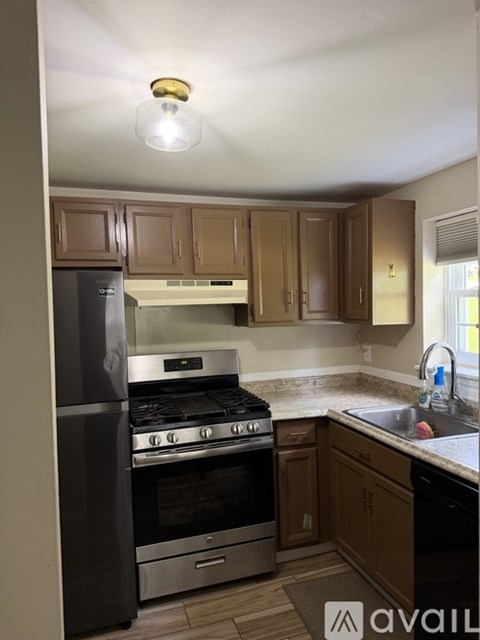 A kitchen with wooden cabinets and a black refrigerator.