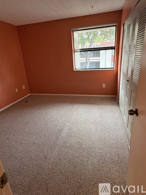 A room with orange walls and a window with a view of a building outside.