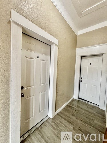 A hallway with two white doors and wooden floors.