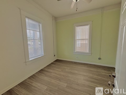 A room with a ceiling fan and two windows.