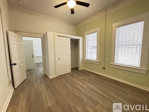 A room with a ceiling fan and wooden flooring.