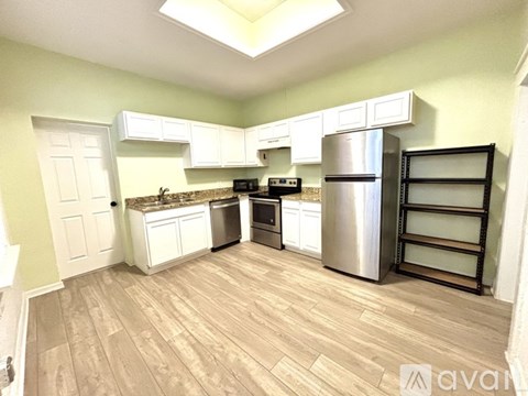A kitchen with white cabinets and a wooden floor.