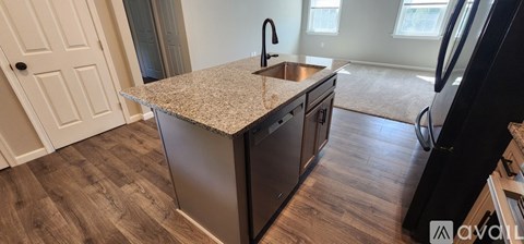 A kitchen with a granite countertop and a black refrigerator.