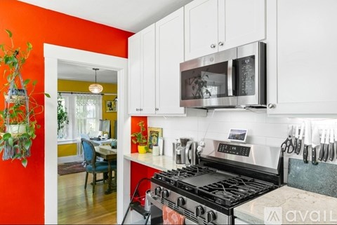 A kitchen with a red wall and a black stove top oven.