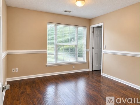 A room with wooden floors and a window with blinds.