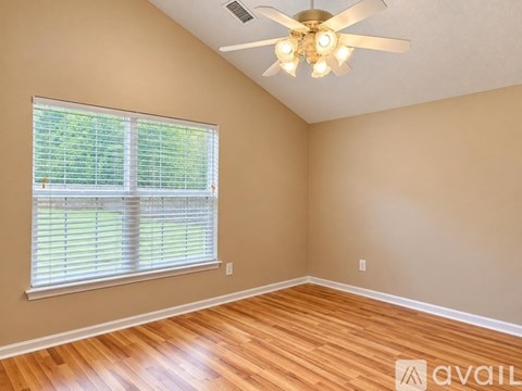 A room with a ceiling fan and a window with blinds.