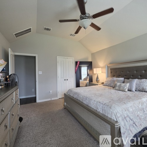 A bedroom with a large bed and a ceiling fan.