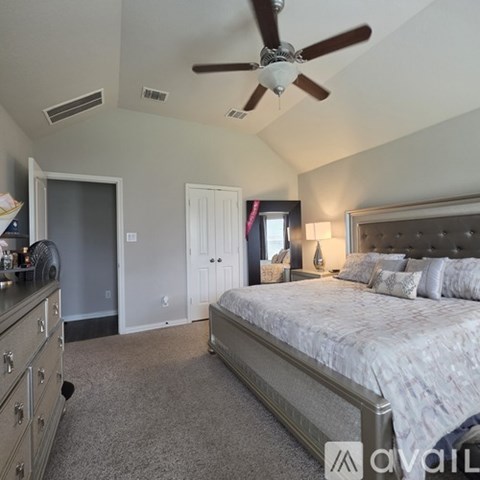 A bedroom with a large bed and a ceiling fan.