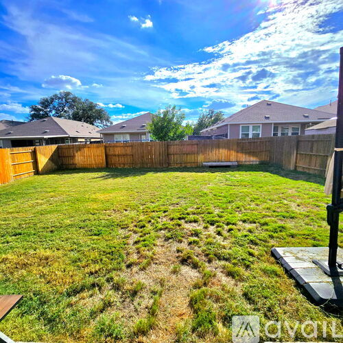A backyard with a wooden fence and a grassy area.