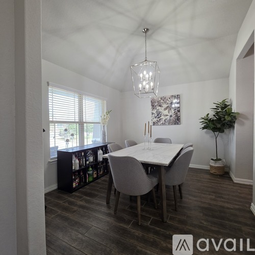 A dining room with a table and chairs and a plant.