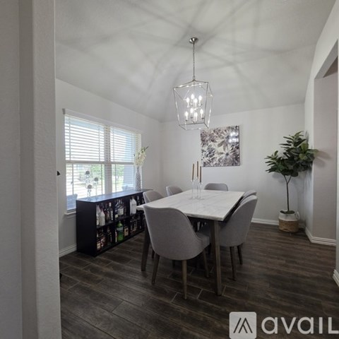 A dining room with a table and chairs and a plant.