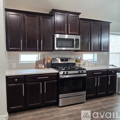 A kitchen with dark brown cabinets and a stainless steel stove.