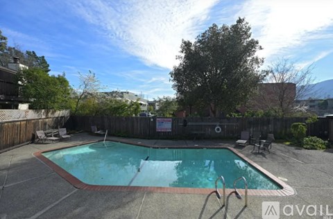 A small pool surrounded by a fence and trees.